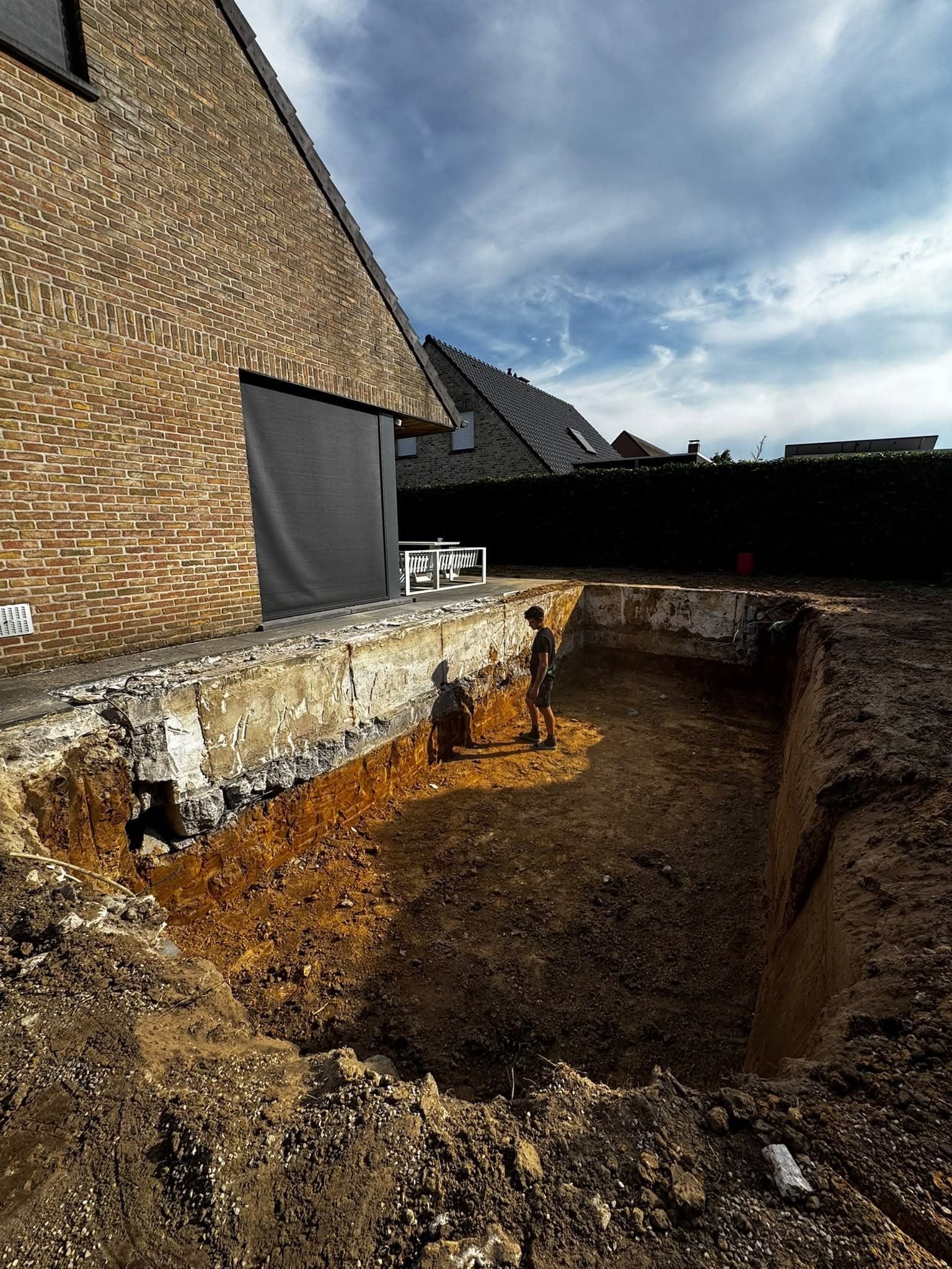 Diepe uitgraving naast een woning, klaar voor de fundering