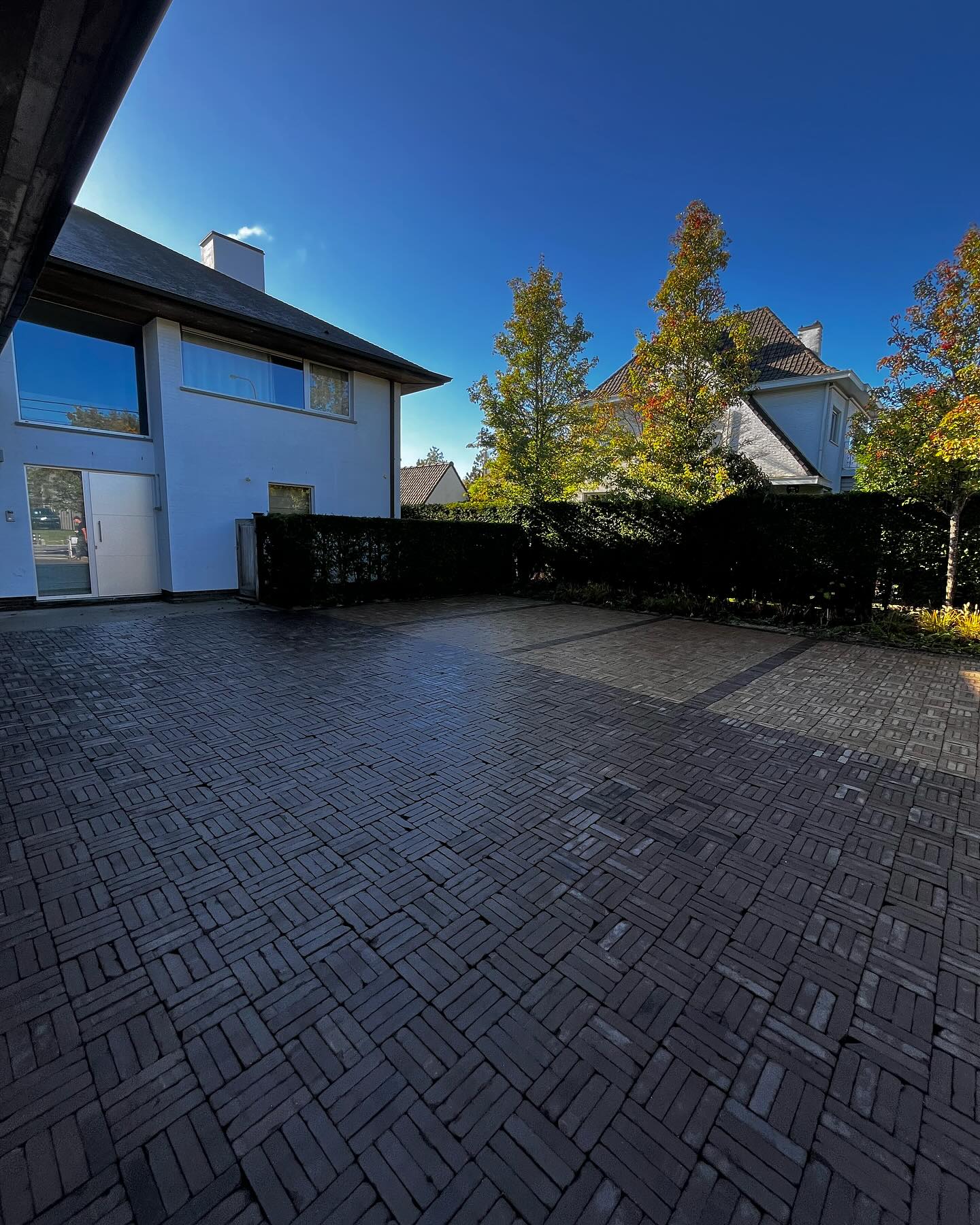 Nieuwe oprit in donkere klinkers voor een woning, door Tuinen Haemers