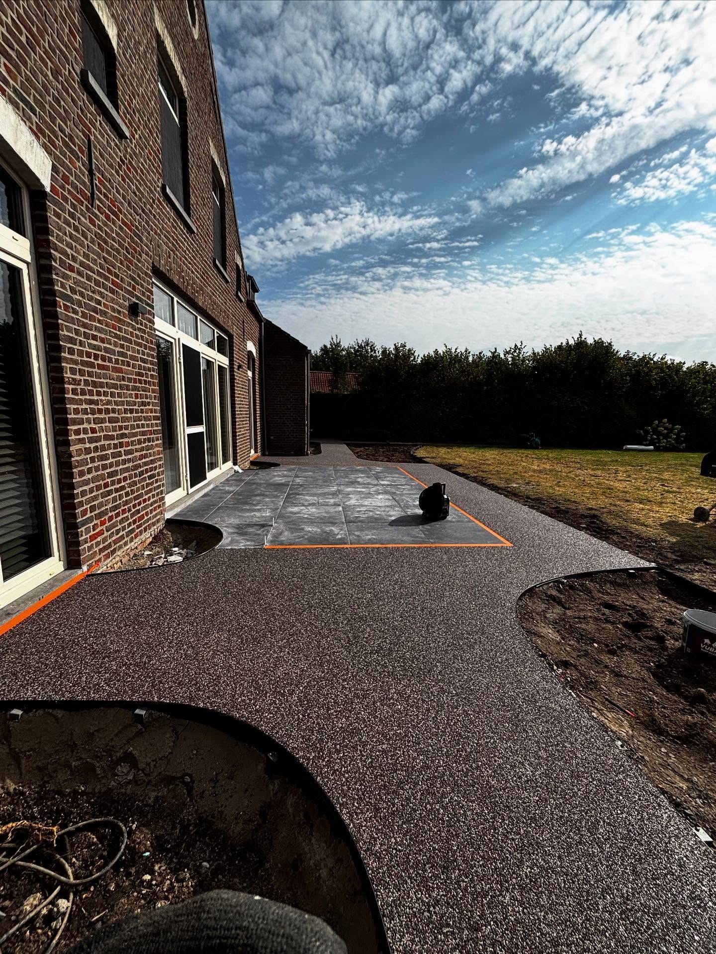 Oprit in steentapijt met een vloeiende bocht, door Tuinen Haemers