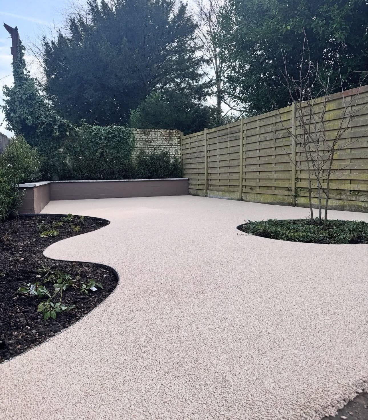 Tuin volledig in steentapijt met vloeiende borders en een jonge boom